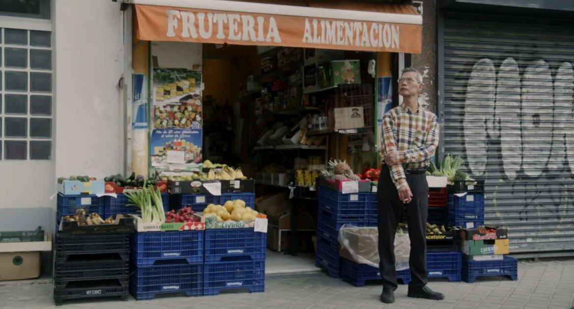 hOMBRE ORIENTAL FRENTE A TIENDA DE COMESTIBLES